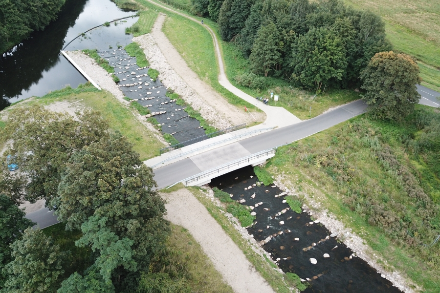 Ein Bild zeigt die Fischtreppe der Nebel bei Lüssow aus der Vogelperspektive. Quer zum Gewässer sind große Steine zu sehen, die unterschiddlich weit aus dem Wasser herausragen. Die Fischtreppe baut ein Gefälle über einen längere Strecke ab und ermöglicht so den im Wasser lebenden Tieren die Wanderung im Gewässer.